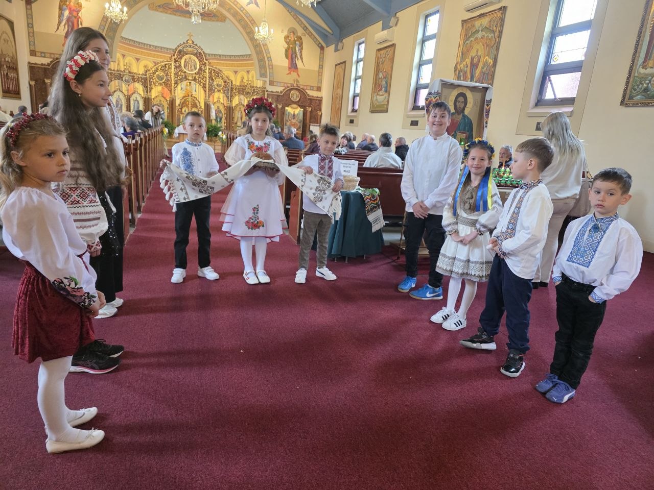 Children in Ukrainian embroidered clothing welcoming parishioners along the church aisle